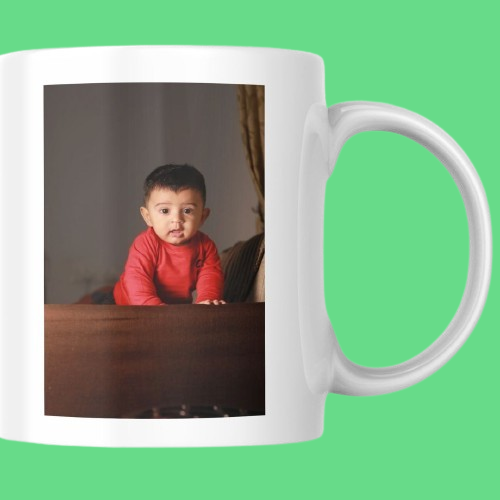 A baby in a red sweater sits on a table, captured in a charming image for a printed mug design